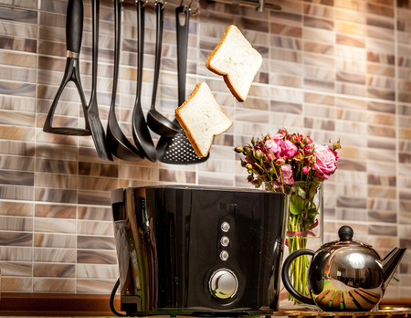 Closeup shot of two slices of bread popping out of toaster on kitchen
