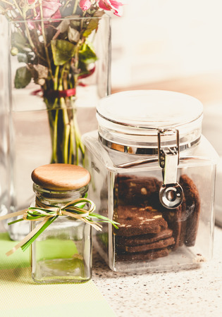 Closeup toned photo of chocolate cookies in glass jar on kitchen tableの写真素材