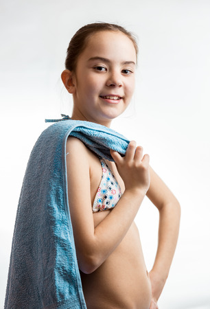Portrait of cute smiling girl posing with blue towel over white backgroundの写真素材