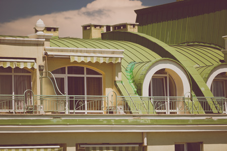 Toned photo of beautiful terrace under green metal roof at classic buildingの写真素材
