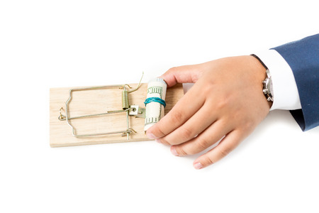 Closeup isolated photo of businessman putting money in mousetrapの写真素材