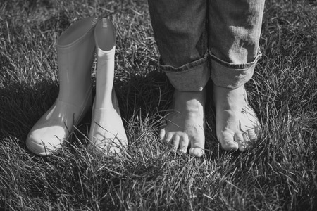 Black and white photo of girl took off gumboots and standing on grassの写真素材