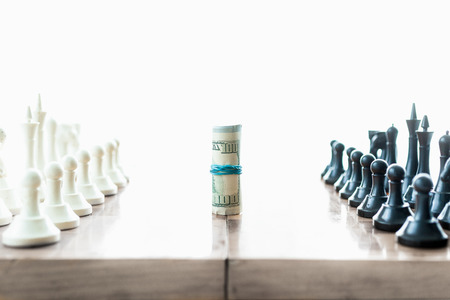 Conceptual shot of chess pieces fighting for twisted dollar billsの写真素材
