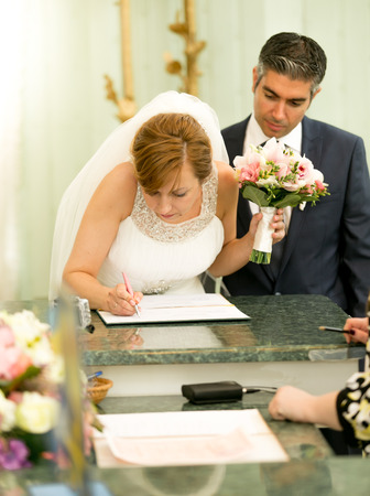 Portrait of young bride signing wedding contract at registry officeの写真素材
