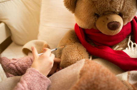 Closeup photo of little girl doing injection to sick teddy bearの写真素材