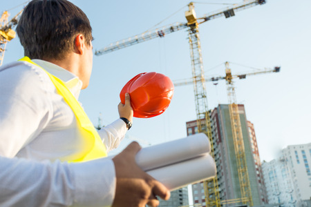 Closeup photo of engineer posing on building site with orange hardhatの素材 [FY31041681919]