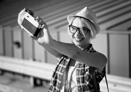 Black and white portrait of smiling hipster girl making selfie on vintage film cameraの写真素材