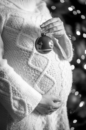 Closeup monochrome photo of pregnant woman posing with Christmas ballの写真素材