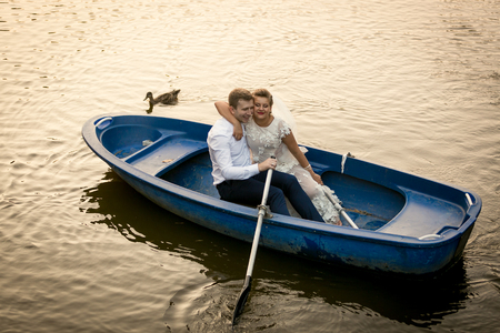 Happy bride and groom embracing on the rowing boatの写真素材