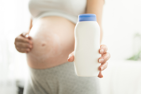 Closeup photo of pregnant woman holding creme container with copy spaceの写真素材