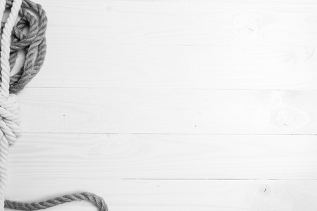 Monochrome shot of sea knots and ropes lying on white wooden planksの写真素材