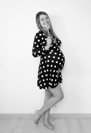 Black and white portrait of cute pregnant woman posing with lollipopの写真素材