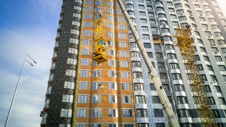 Big industrial crane descend building crane cabin at building siteの写真素材