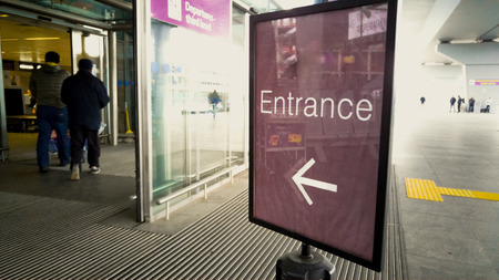 Entrance sign at modern airport with automatic glass doors