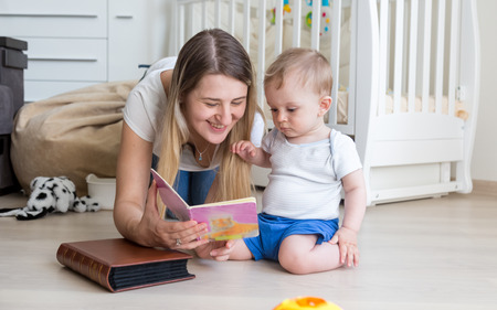 Portrait of beautiful young mother reading book to her baby boy