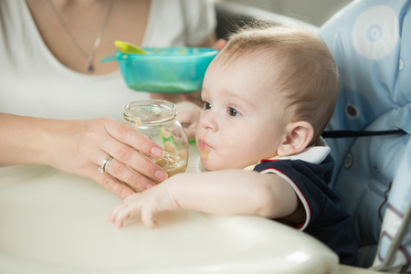 Closeup photo of mother feeding baby boy with porridgeの写真素材