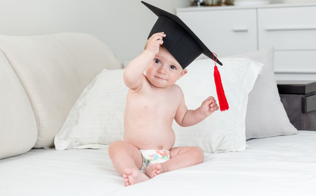 Adorable 10 months old baby boy in black graduation cap with tasselの写真素材