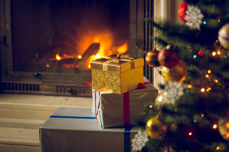Toned image of beautiful Christmas tree and stack of presents in front of burning fireplaceの写真素材