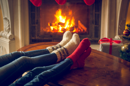 Closeup toned image of female and and feet in wool socks warming at fireplace at chaletの写真素材