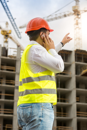Portrait of construction engineer pointing with finger at building under constructionの写真素材