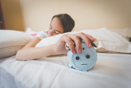 Closeup photo of young woman turning off alarm clockの写真素材