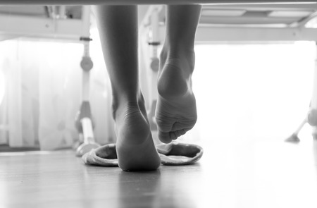 Black and white closeup photo of from under the bed on woman wearing slippers at morningの写真素材