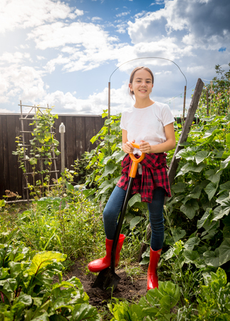 Happy young girl in red gumboots working at backyard gardenの写真素材