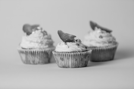 Closeup black and white photo of three tasty cupcakes over background in studioの写真素材