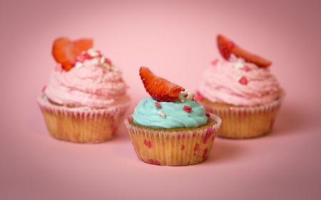 Macro shot of three decorated cupcakes with blue and pink buttercreamの写真素材
