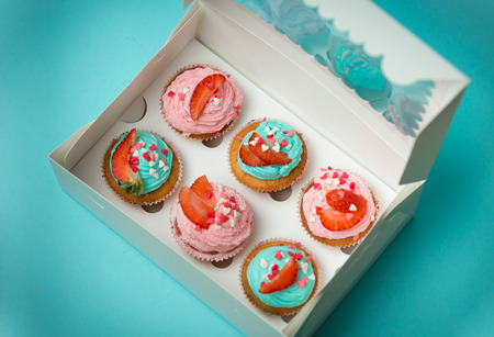 Closeup photo of open paper box with six colorful cupcakesの写真素材