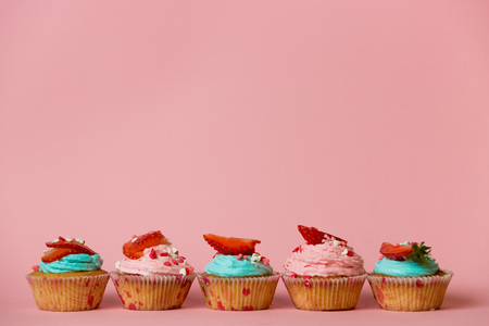 Colorful cupcakes with sprinkles and berries on topの写真素材