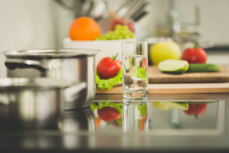 Toned image of fresh vegetables lying next to electric stove on modern kitchenの写真素材