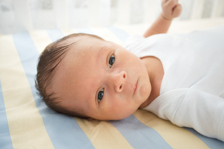 Closeup portrait of cute newborn baby lying in bedの写真素材