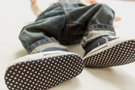 Closeup photo of baby boy feet in jeans and sneakersの写真素材