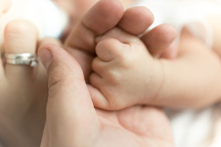 Closeup image of man holding newborn baby\s hand