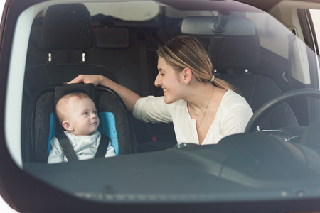 Portrait of beautiful mother at her baby sitting in child seat at carの写真素材