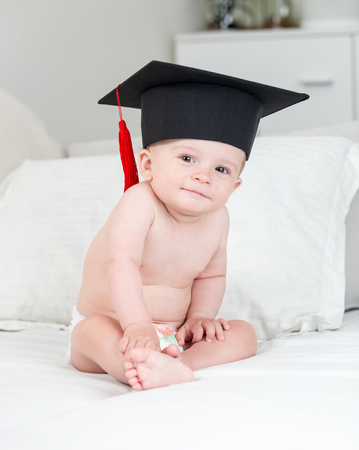 10 months old baby boy in black graduation cap with tasselの写真素材