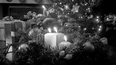 Black and white image of Christmas candles in wreath on decorated table at living roomの写真素材