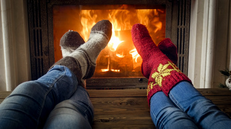Young couple in warm knitted socks relaxing in chalet at fireplaceの写真素材