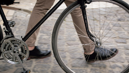 Closeup image of male feet next to vintage bicycle on paved roadの写真素材