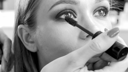 Black and white image of professional makeup artist painting models eyes with mascaraの写真素材