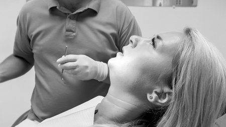 Black and white image of young woman lying in dentist chairの写真素材