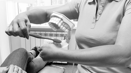 Black and white image of dentist showing hor to properly clean teeth