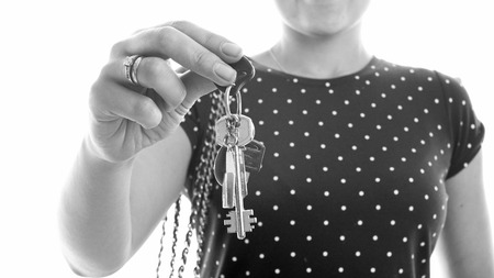 Black and white closeup photo of young woman holding keys from new houseの写真素材