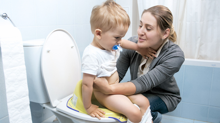 Young woman searing her toddler boy on toiletの写真素材