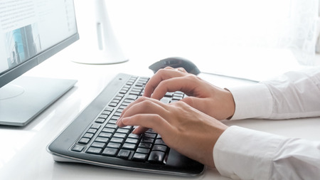 Closeup photo of young businesswoman typing e-mail on keyboardの写真素材