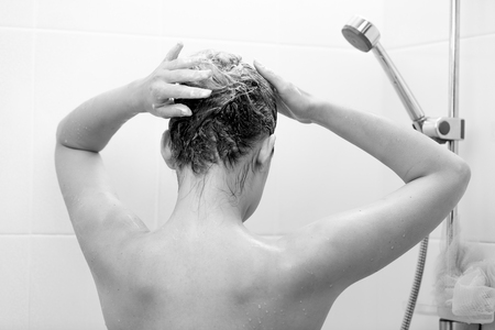 Closeup black and white photo of young brunette woman washing hair with shampooの写真素材