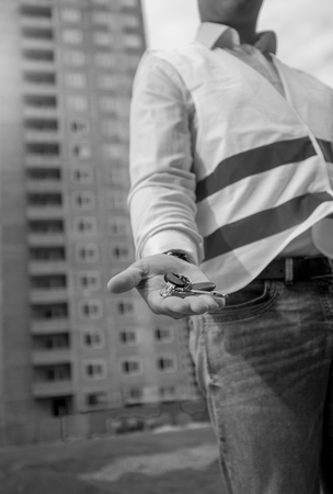 Closeup black and white image of male architect holding keys from new apartment on handの写真素材