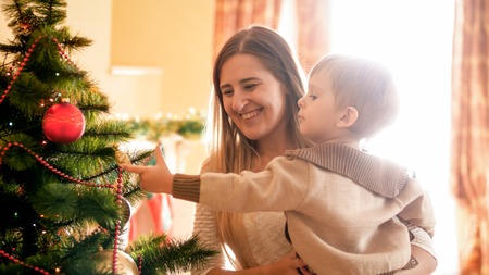 Portrait of happy laughing young woman with her little child decorating Chrismtas treeの写真素材