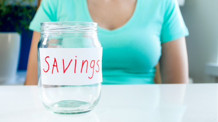 Closeup photo of young woman with financial problems sitting with empty glass jar for money savings